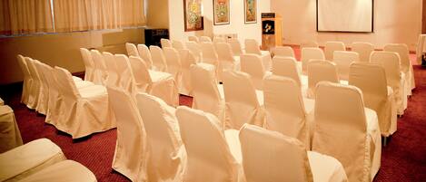 Una sala conferenze con file di sedie coperte di bianco e pavimento tappezzato.