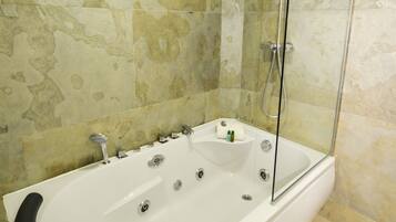 A modern bathroom with a freestanding bathtub, a glass shower enclosure, and a stone-textured wall.