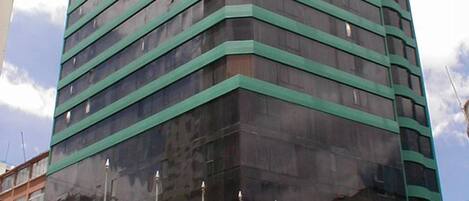A tall, modern building with a reflective glass facade and a green accent.