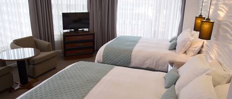 Habitación de hotel con dos camas, televisor, escritorio y silla.