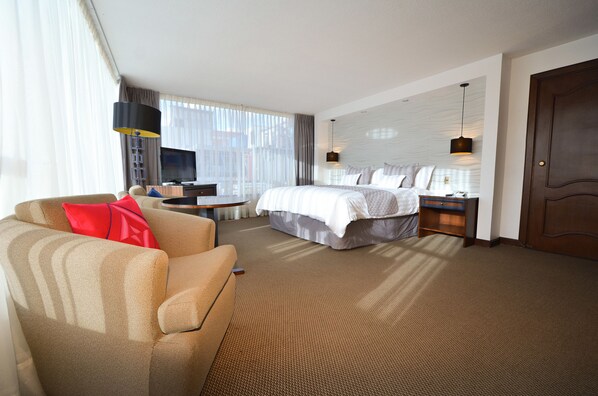 Una habitación de hotel con una cama, un sofá, un televisor, un escritorio y una puerta.