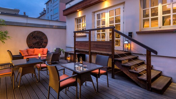 An outdoor deck with a dining area, a sofa, and a staircase leading to an upper level. - Best Western Plus Hotel Villa D'est (Strasbourg)