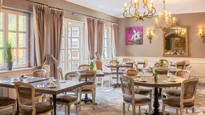 A dining area with multiple tables and chairs, a chandelier, and large windows with curtains. - Best Western Plus Hotel Villa D'est (Strasbourg)