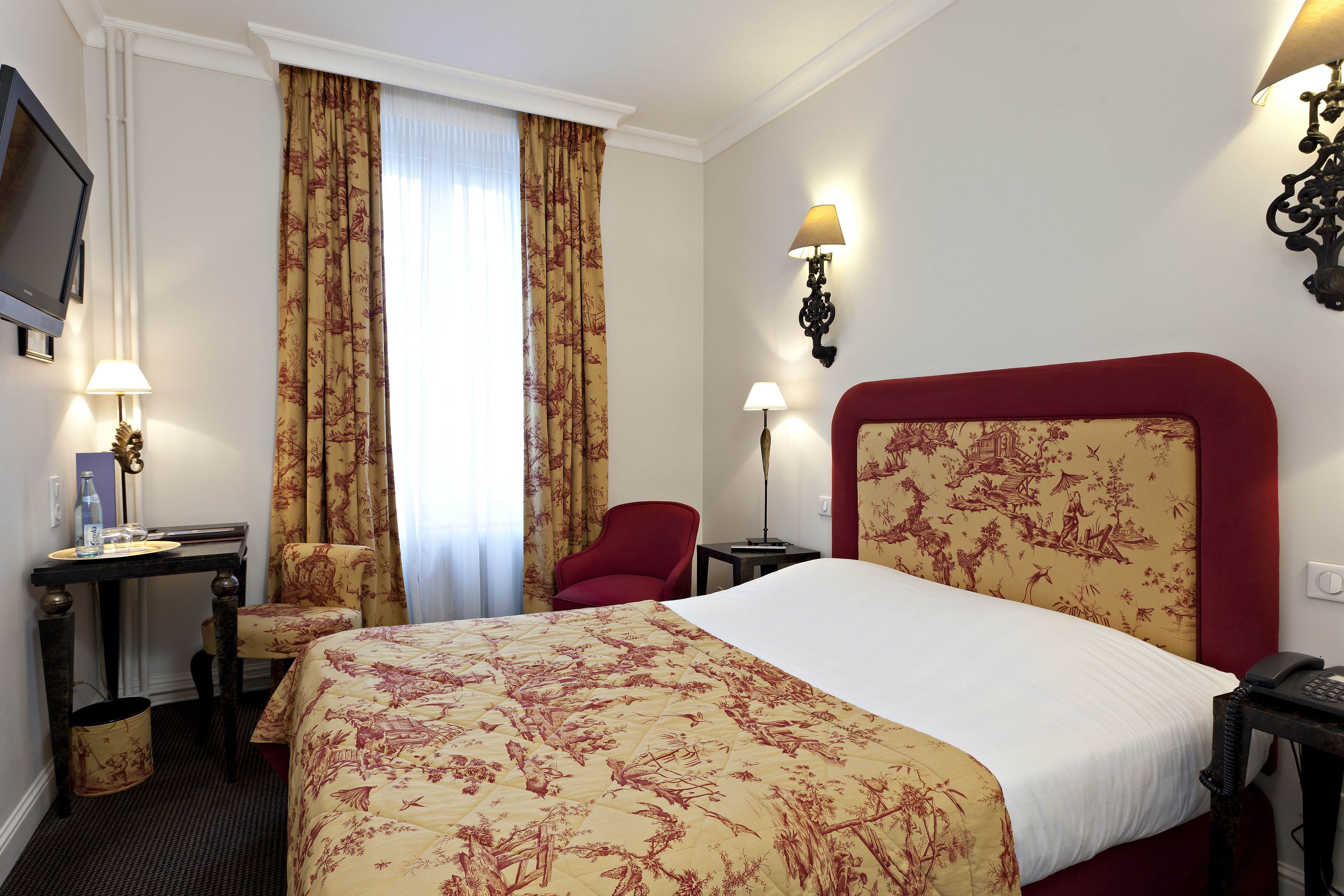 Habitación de hotel con una cama grande, un escritorio con una silla, televisión y dos lámparas.