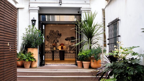A hotel entrance with steps leading up to a door, surrounded by potted plants. - Hotel Kyriad Paris 10 Canal Saint Martin (Paris)
