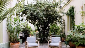 An outdoor seating area with two chairs, surrounded by potted plants and a tree. - Hotel Kyriad Paris 10 Canal Saint Martin (Paris)