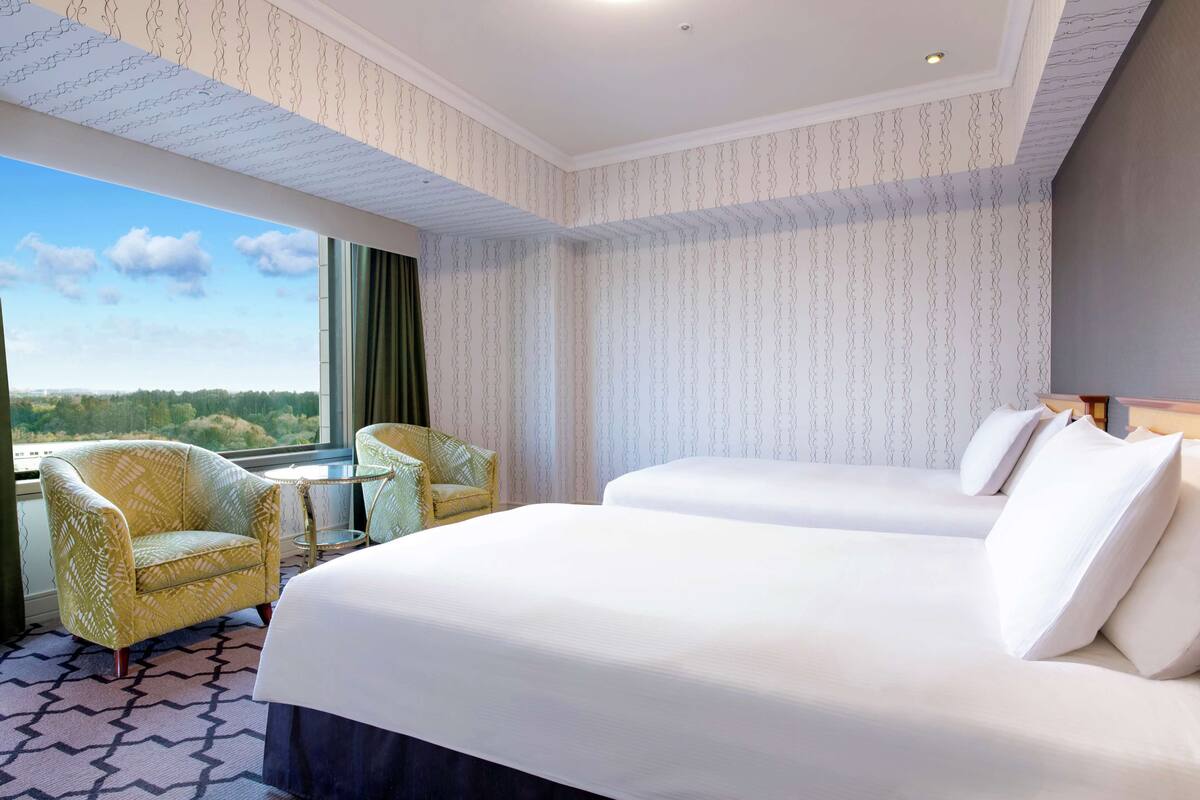 Habitación de hotel con dos camas, una mesita y una silla.
