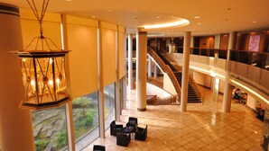 Eine geräumige Lobby mit hoher Decke, großen Fenstern und einer zentralen Treppe.