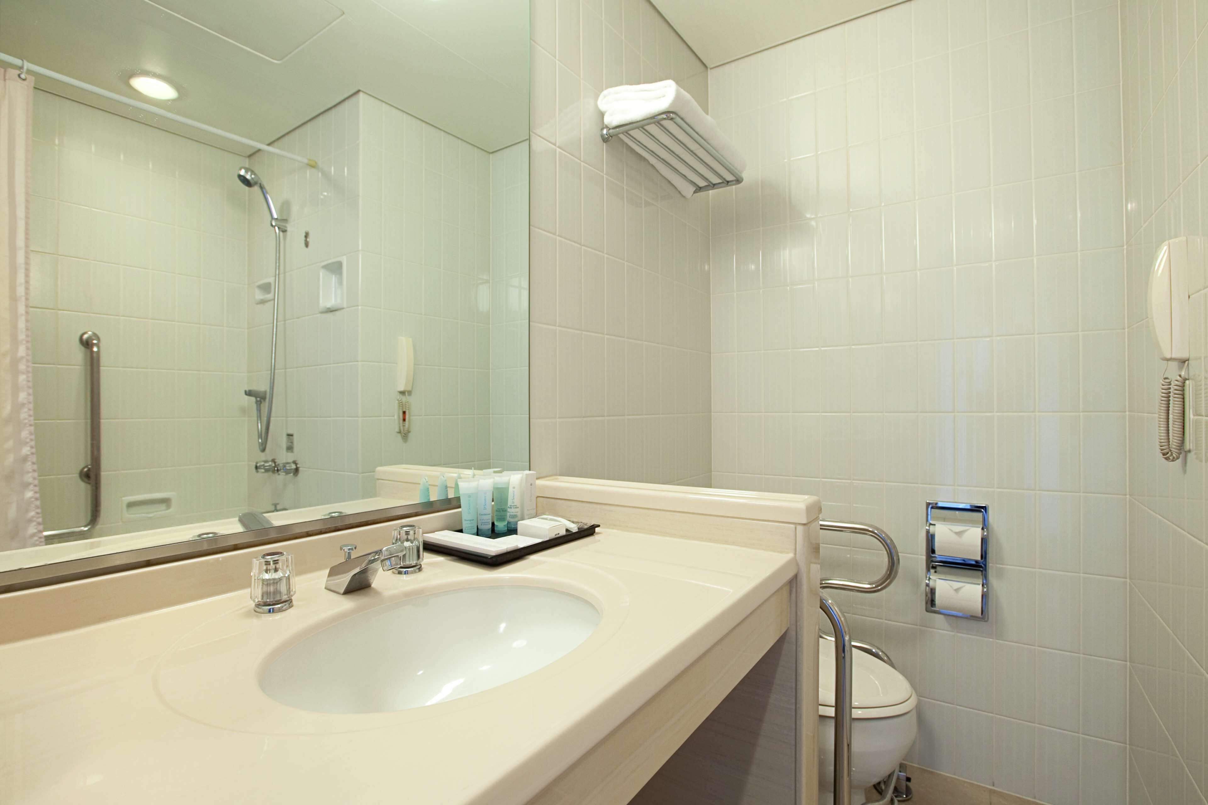 A modern bathroom with a sink, mirror, and toilet.