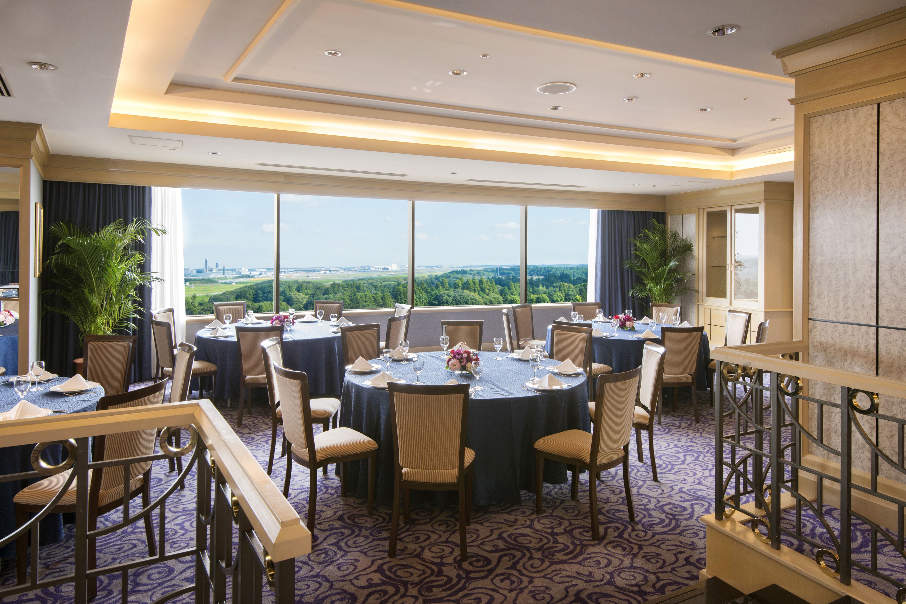 A conference room with round tables, chairs, and a view of a cityscape.