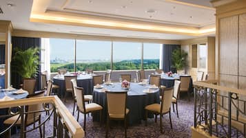 A conference room with round tables, chairs, and a view of a cityscape.