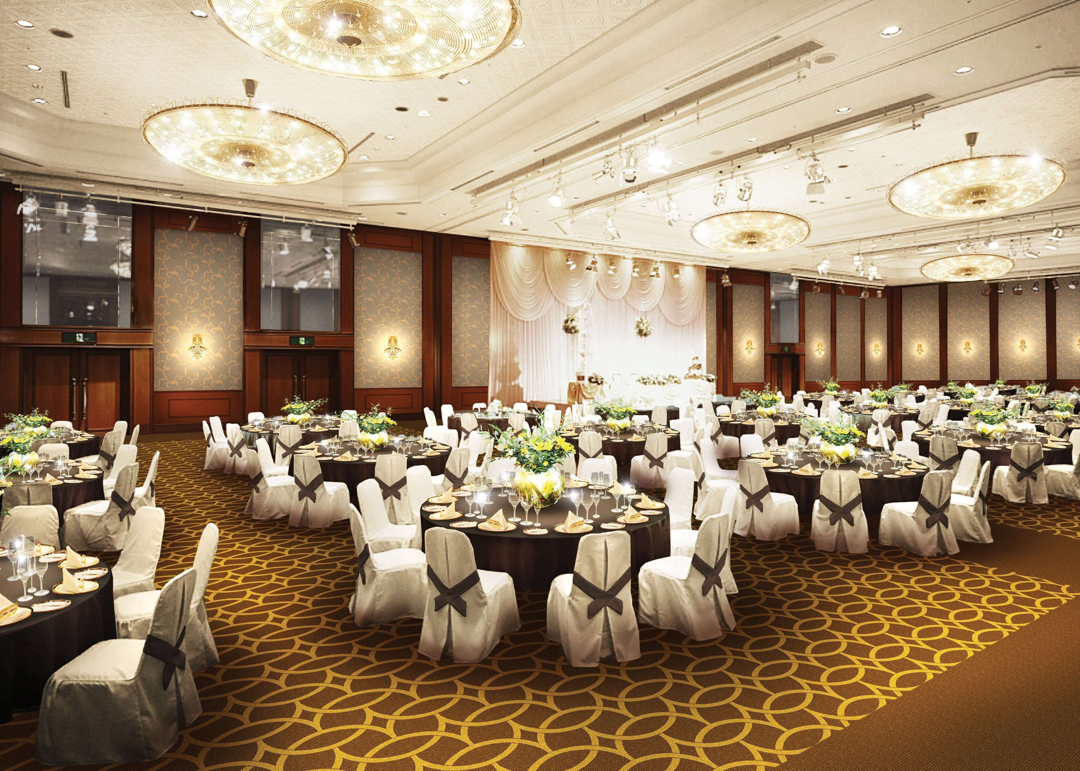 Une vaste salle de banquet avec des tables rondes, des chaises blanches et des lustres.