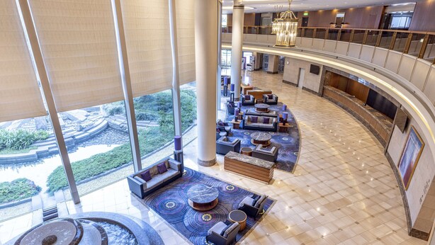 Eine geräumige Lobby mit hoher Decke, einer zentralen Wasserspüle und einer Sitzecke mit Sofas und Sesseln.