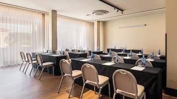 Un salón de conferencias con varias mesas, sillas y botellas de agua.
