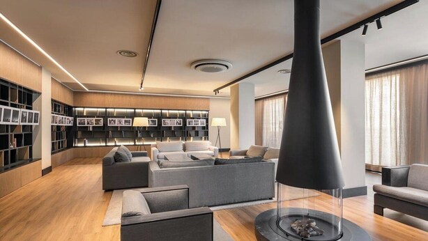 Una sala moderna con chimenea, sofás y una estantería.
