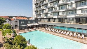 Un hotel con piscina en la azotea, varios balcones y un diseño arquitectónico moderno.