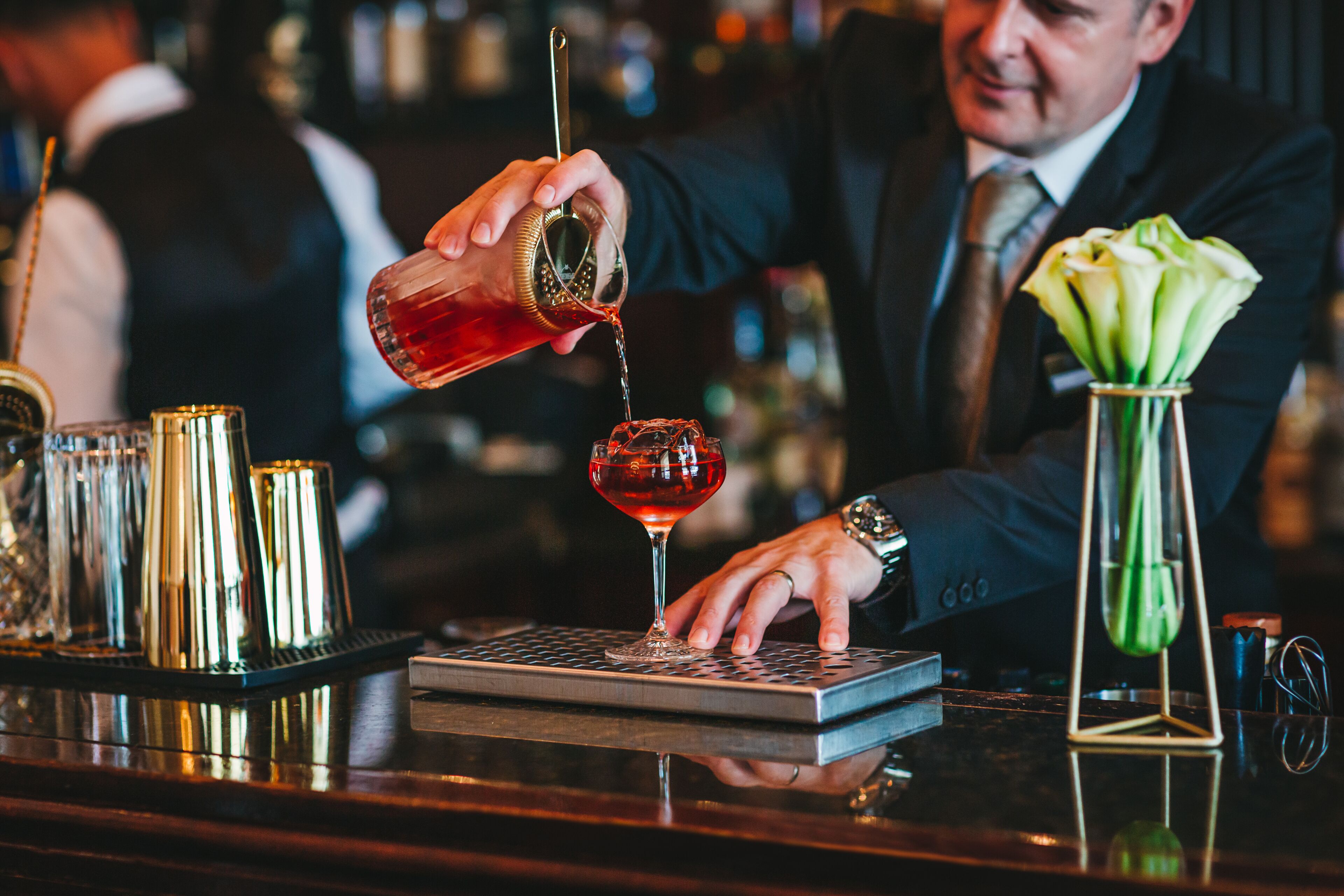 A bartender pouring a drink into a glass.