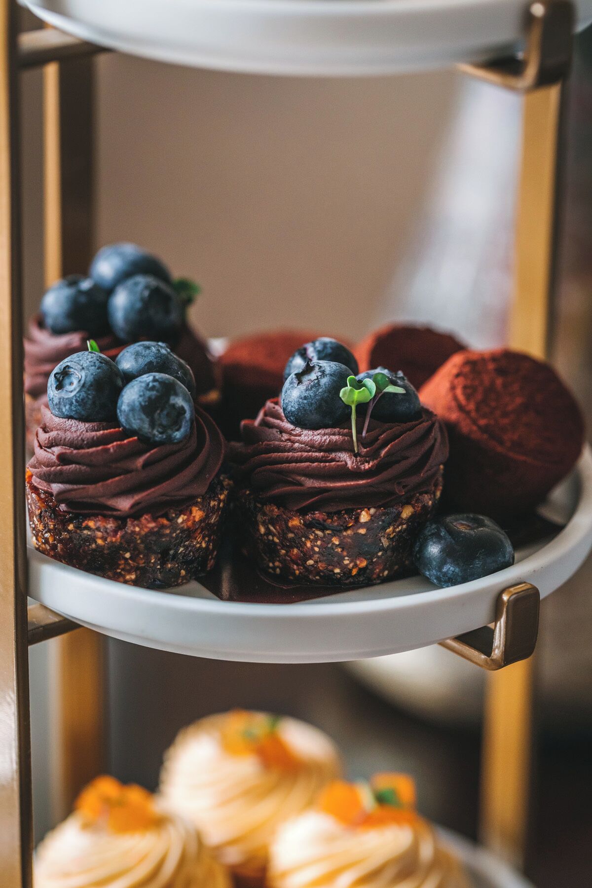 Eine Dessertauslage mit Schokoladen-Cupcakes, belegt mit Blaubeeren, und einem Schokoladenkuchen.