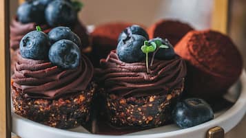 Eine Dessertauslage mit Schokoladen-Cupcakes, belegt mit Blaubeeren, und einem Schokoladenkuchen.