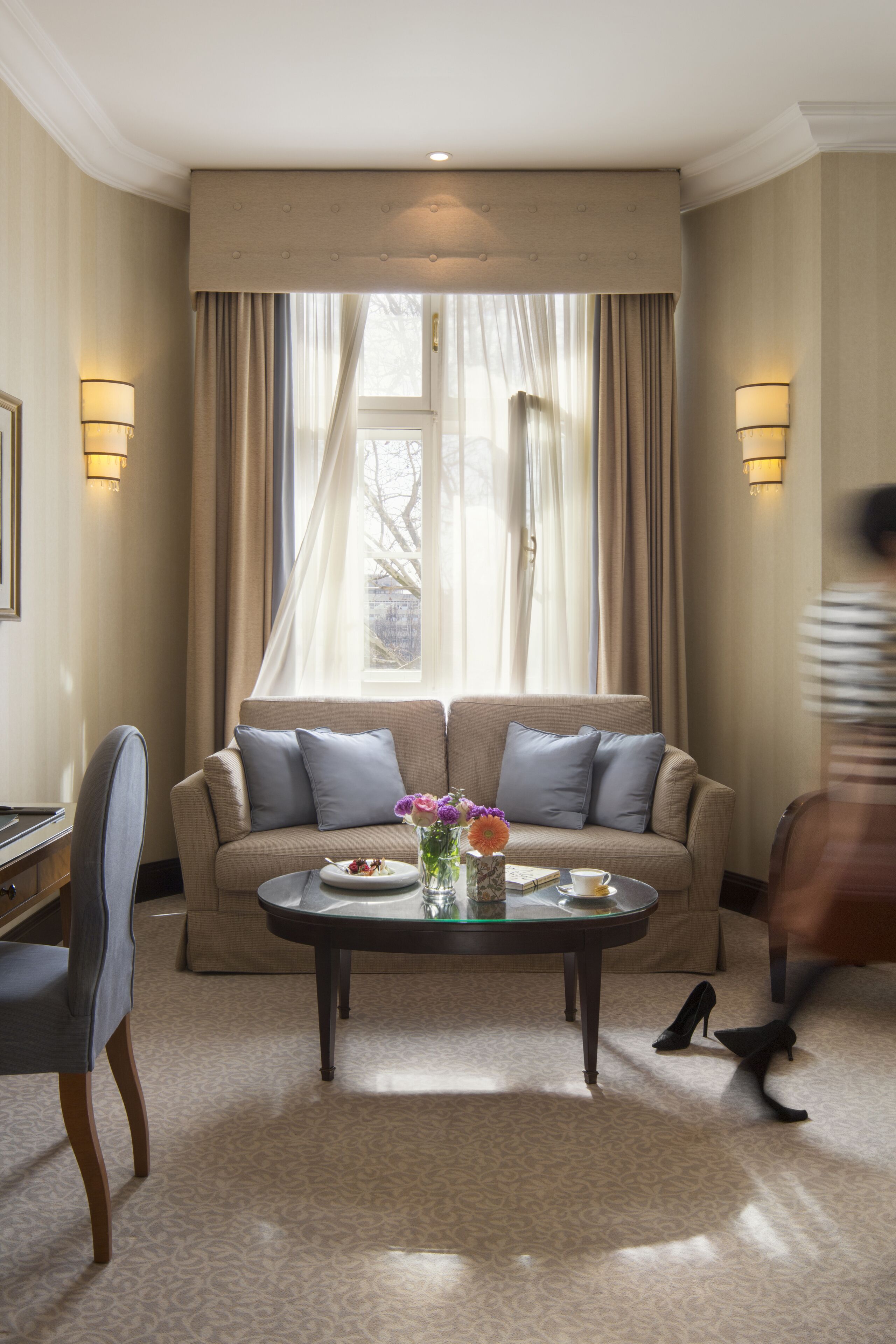 Una habitación de hotel con sofá, una mesita de centro y ventana con cortinas.