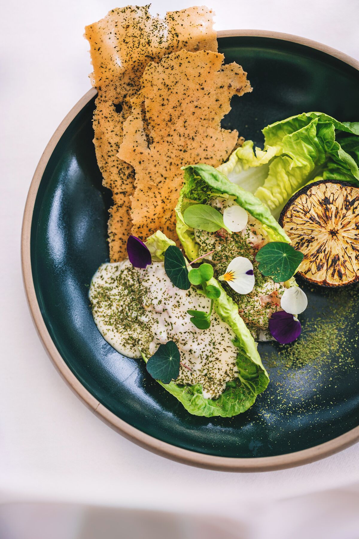 A plate with a salad, a grilled vegetable, and a piece of bread.