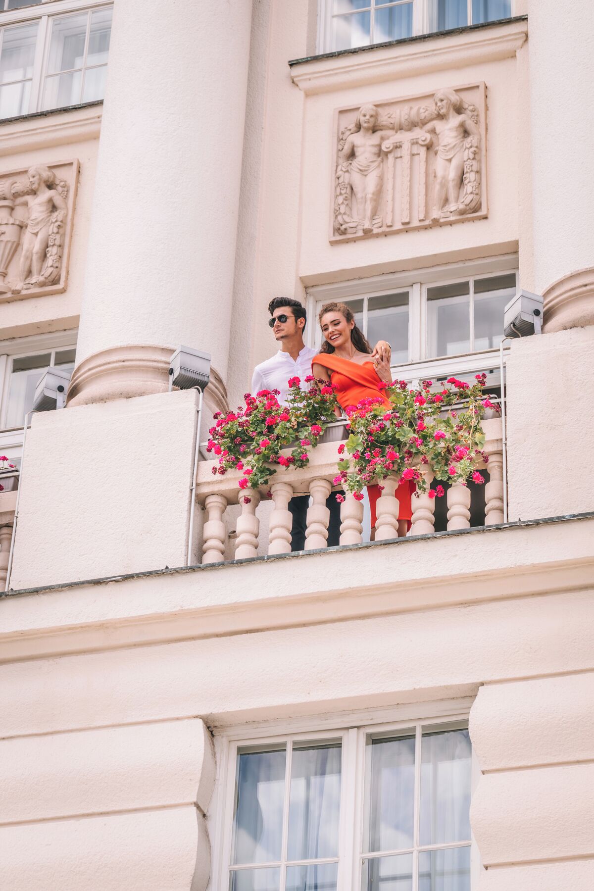 A balcony with a railing, a building facade with classical architectural elements, and a window.
