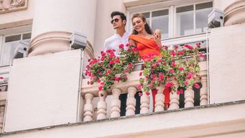 A balcony with a railing, a building facade with classical architectural elements, and a window.
