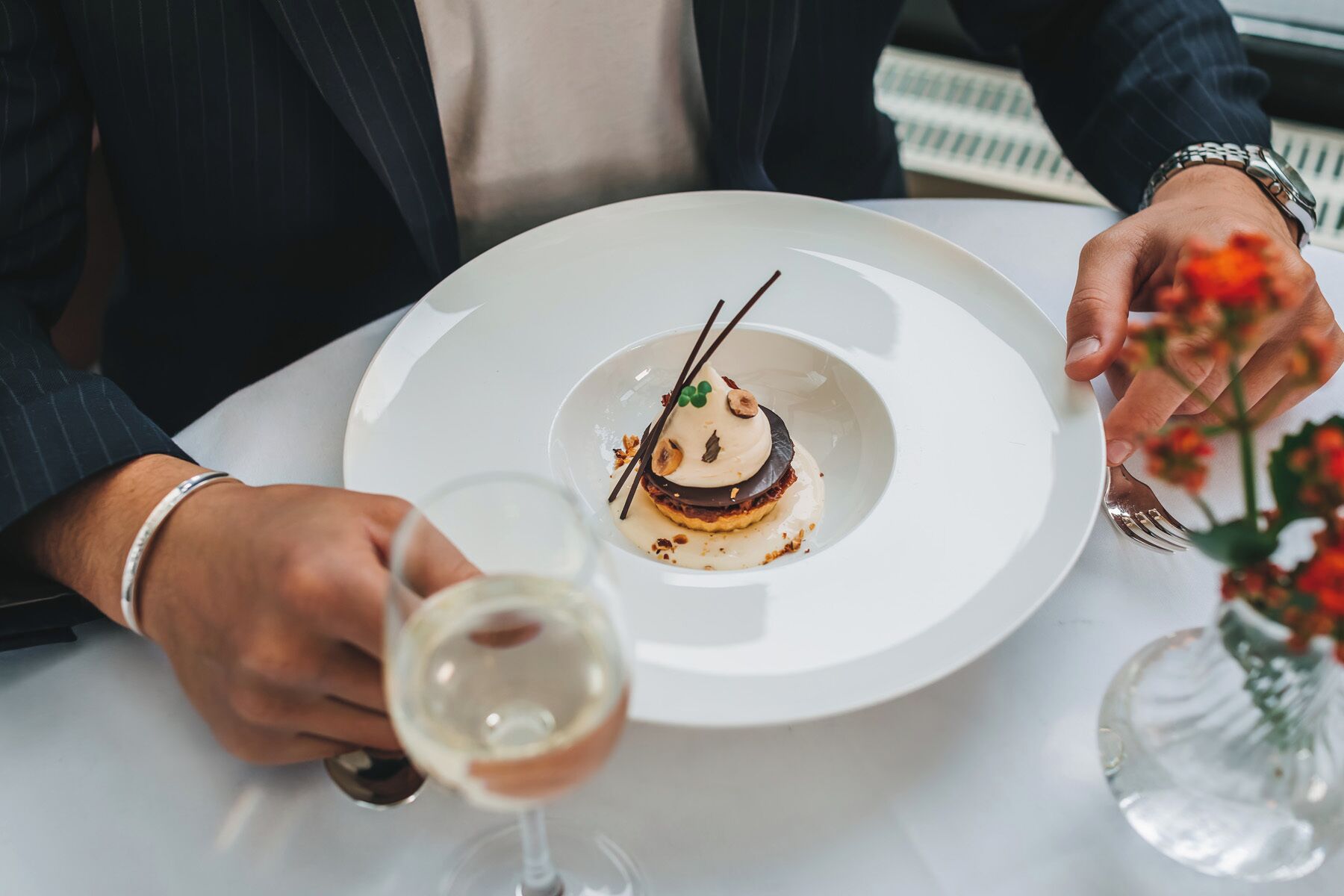 Iemand houdt een wijnglas en een bord met dessert vast.