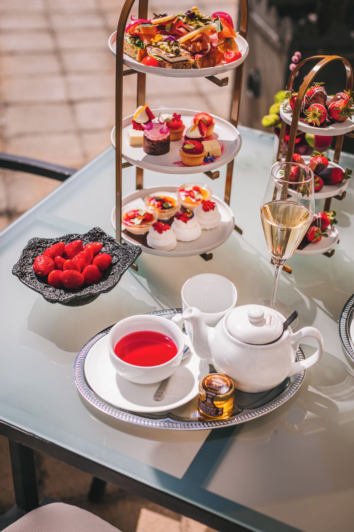 Un présentoir à trois niveaux, garni de diverses pâtisseries, et une coupe de champagne.