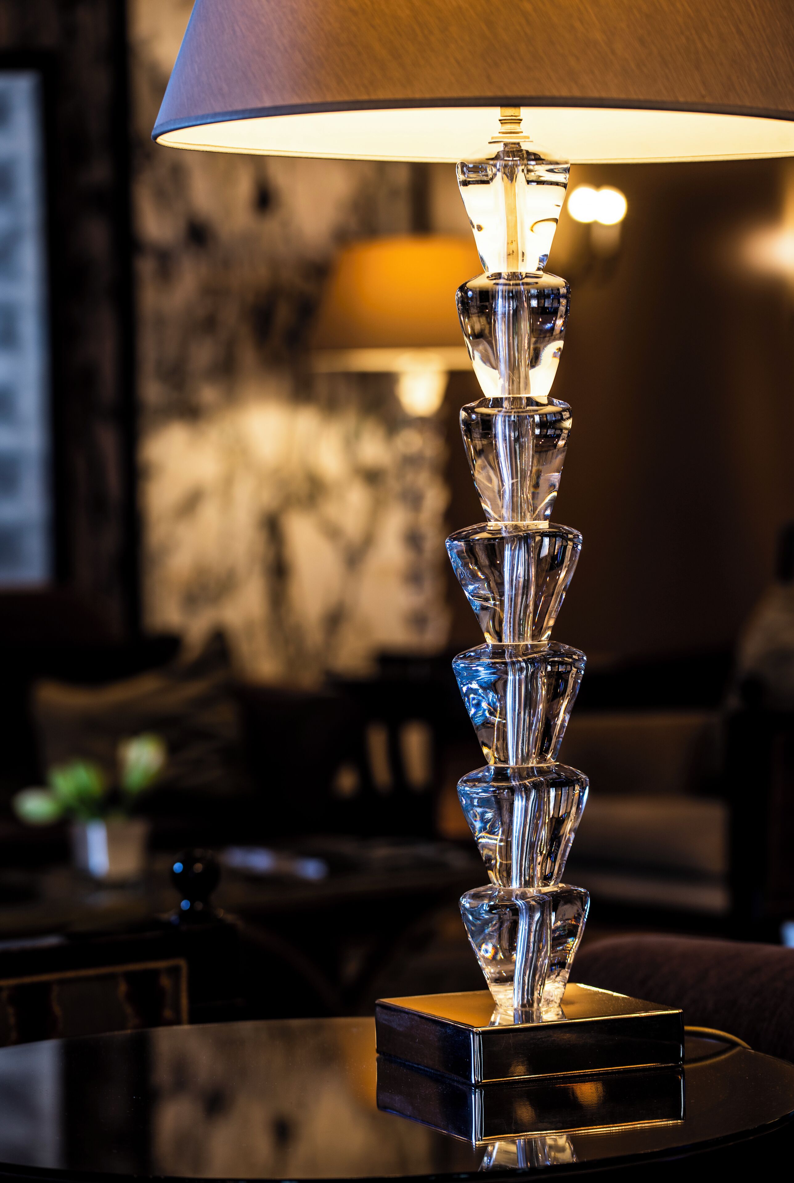 A modern table lamp with a clear, geometric design on a reflective base.