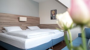 Une chambre d’hôtel moderne, dotée d’un grand lit, d’une table de chevet, d’une chaise et d’une lampe fixée au mur.
