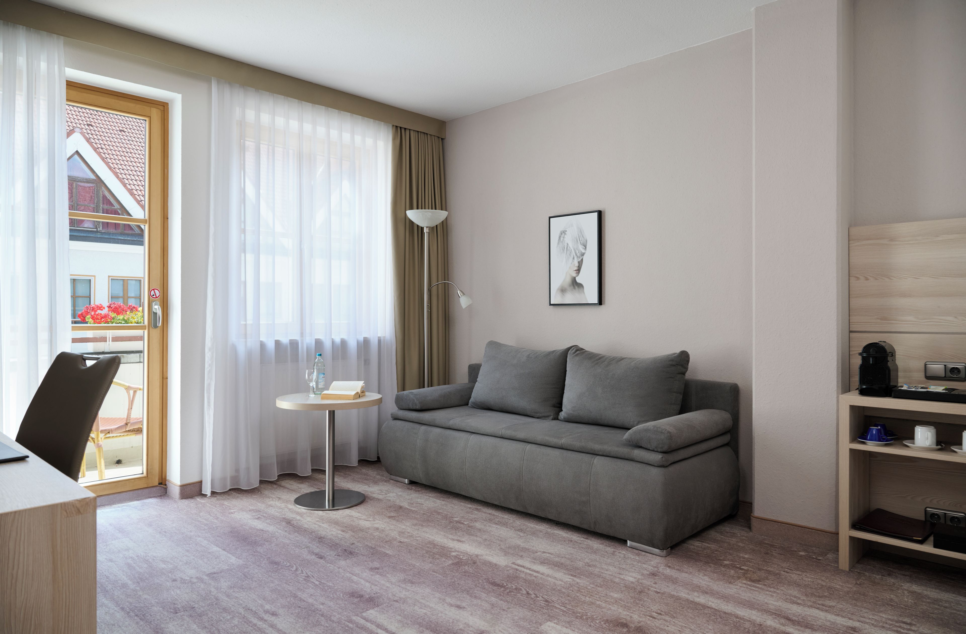 A modern living room with a grey sofa, a small round table, and a floor lamp.