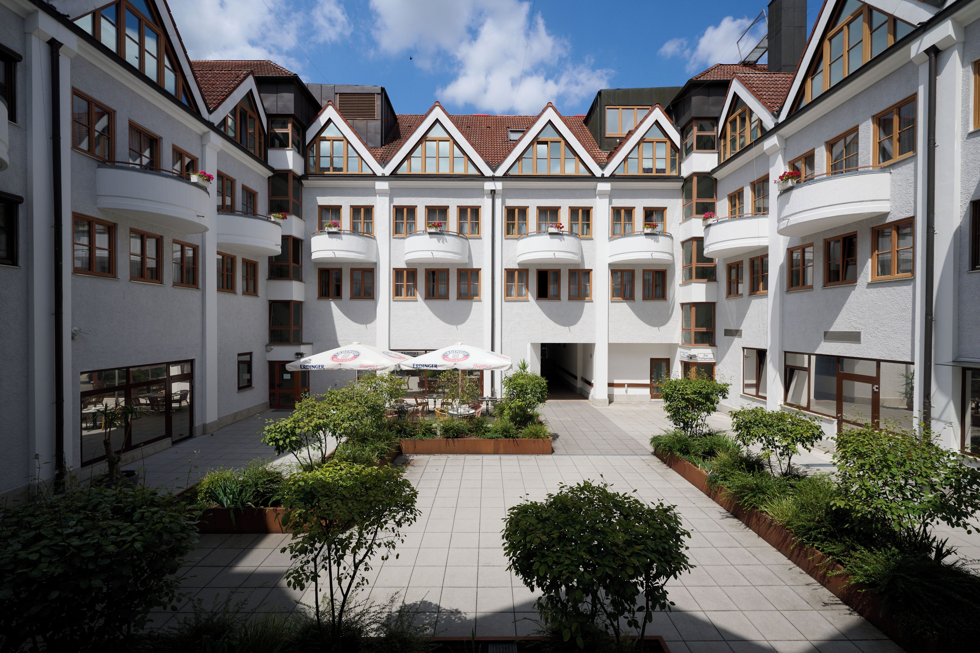 Ein Innenhof mit mehreren Balkonen, Sitzgelegenheiten im Freien und Kübelpflanzen.
