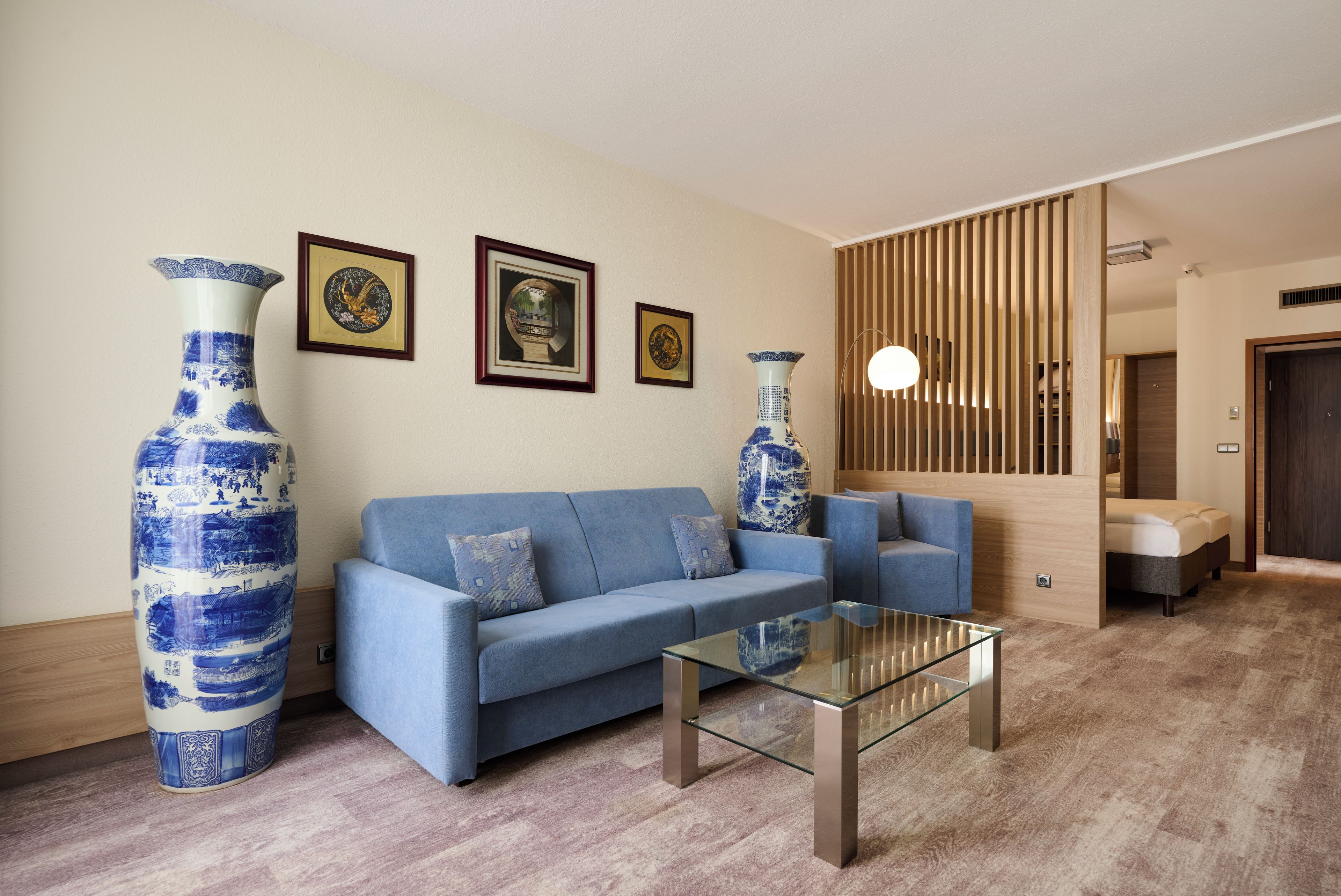 Un salon moderne avec un canapé bleu, une table basse en verre et deux grands vases.