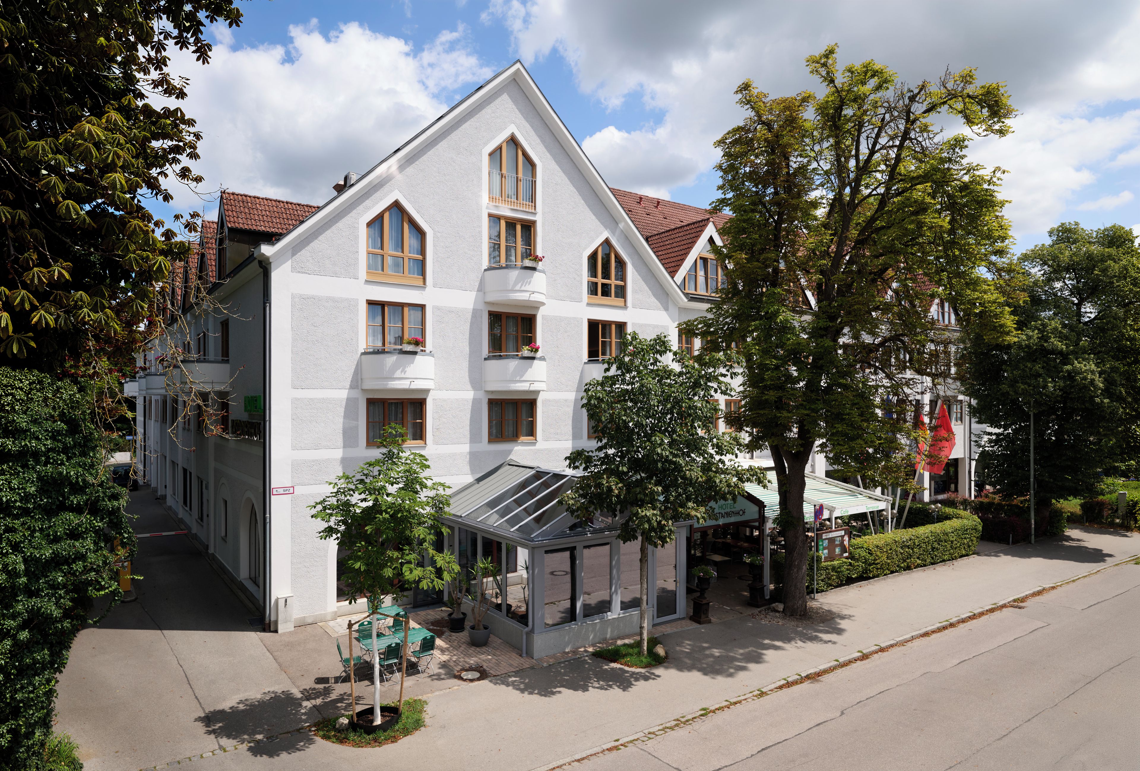 Ein zweistöckiges Gebäude mit Satteldach, zahlreichen Fenstern und einer überdachten Außenbereich-Sitzgelegenheit.