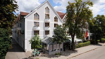 Ein zweistöckiges Gebäude mit Satteldach, zahlreichen Fenstern und einer überdachten Außenbereich-Sitzgelegenheit.