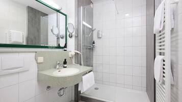 A modern bathroom with a sink, mirror, and shower.