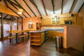 A kitchen with wooden cabinets, a microwave, and a sink. There is a dining area with a table and chairs.