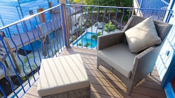 A balcony with wicker furniture, a small pool, and a view of the surrounding area.