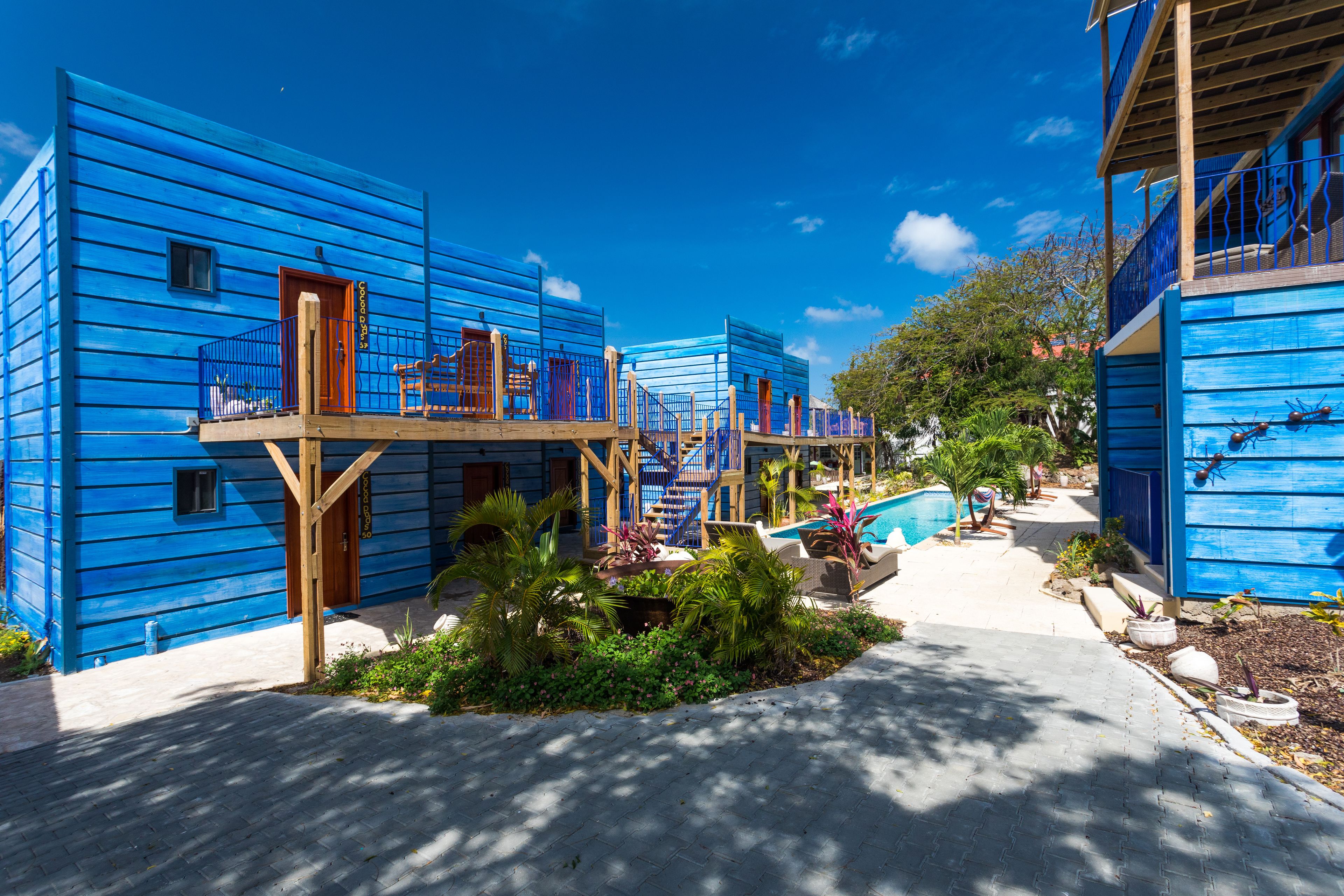 Una hilera de edificios azules con balcones, piscina y jardín.