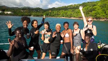 A group of people on a boat with a view of a coastline and hills in the background.