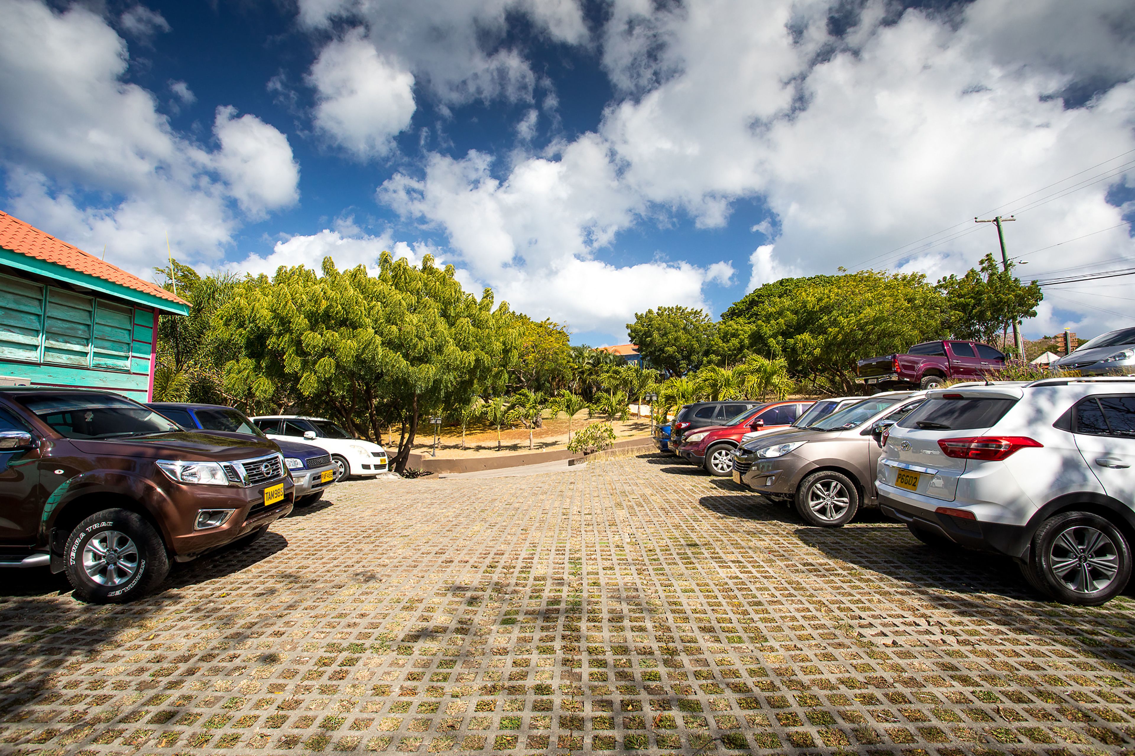 A parking lot with multiple cars and a building with a red roof.