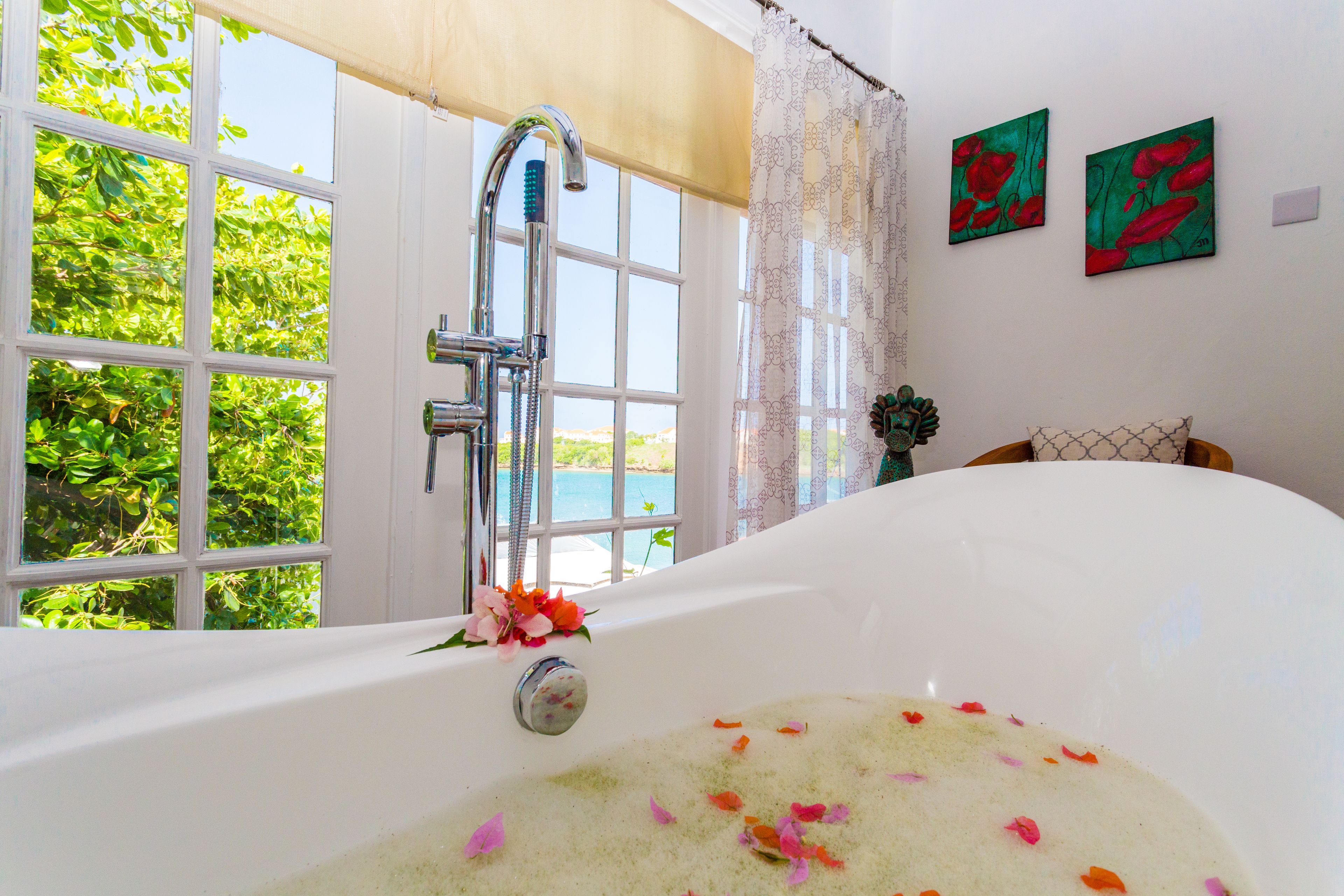 A large bathtub with a view of greenery and a window.