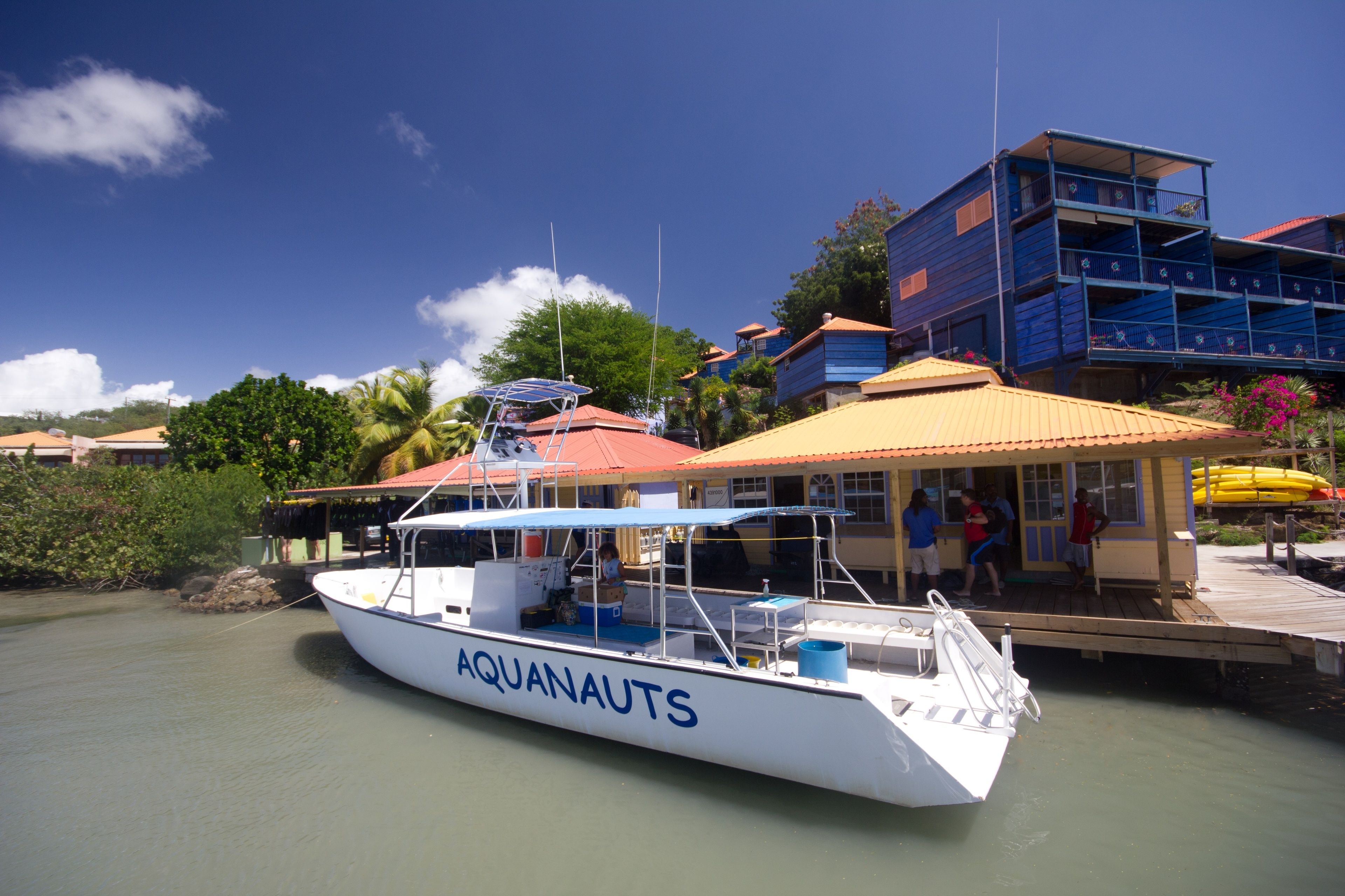 Un barco llamado AQUANAUTS atracado en un muelle, con un edificio al fondo.