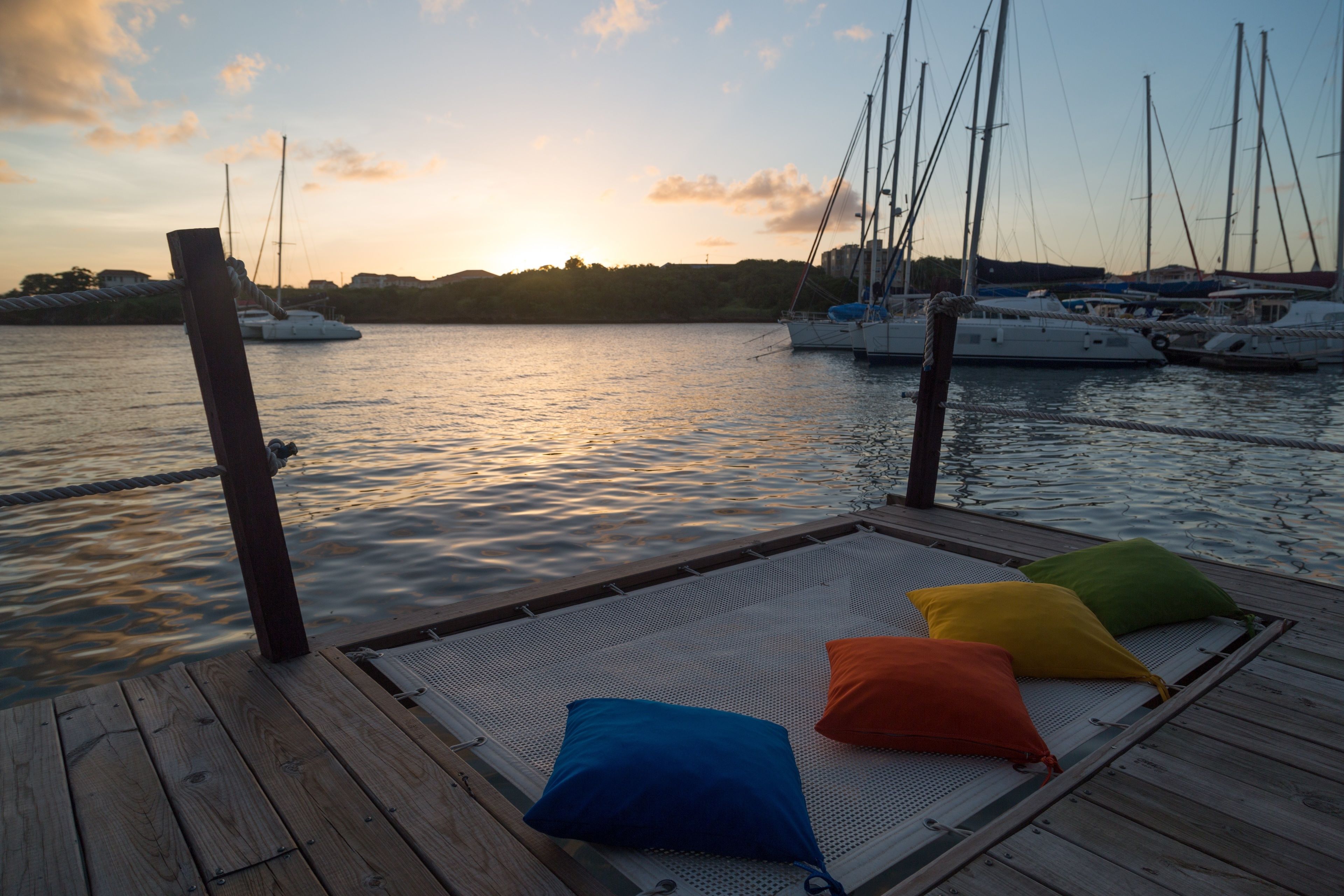 Une terrasse en bois avec un espace détente agrémenté d’un revêtement en treillis blanc et d’une rangée de coussins colorés.