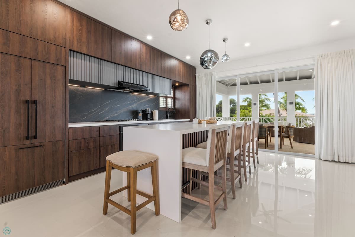 A modern kitchen with dark wood cabinets, a marble countertop, and a central island with bar stools.