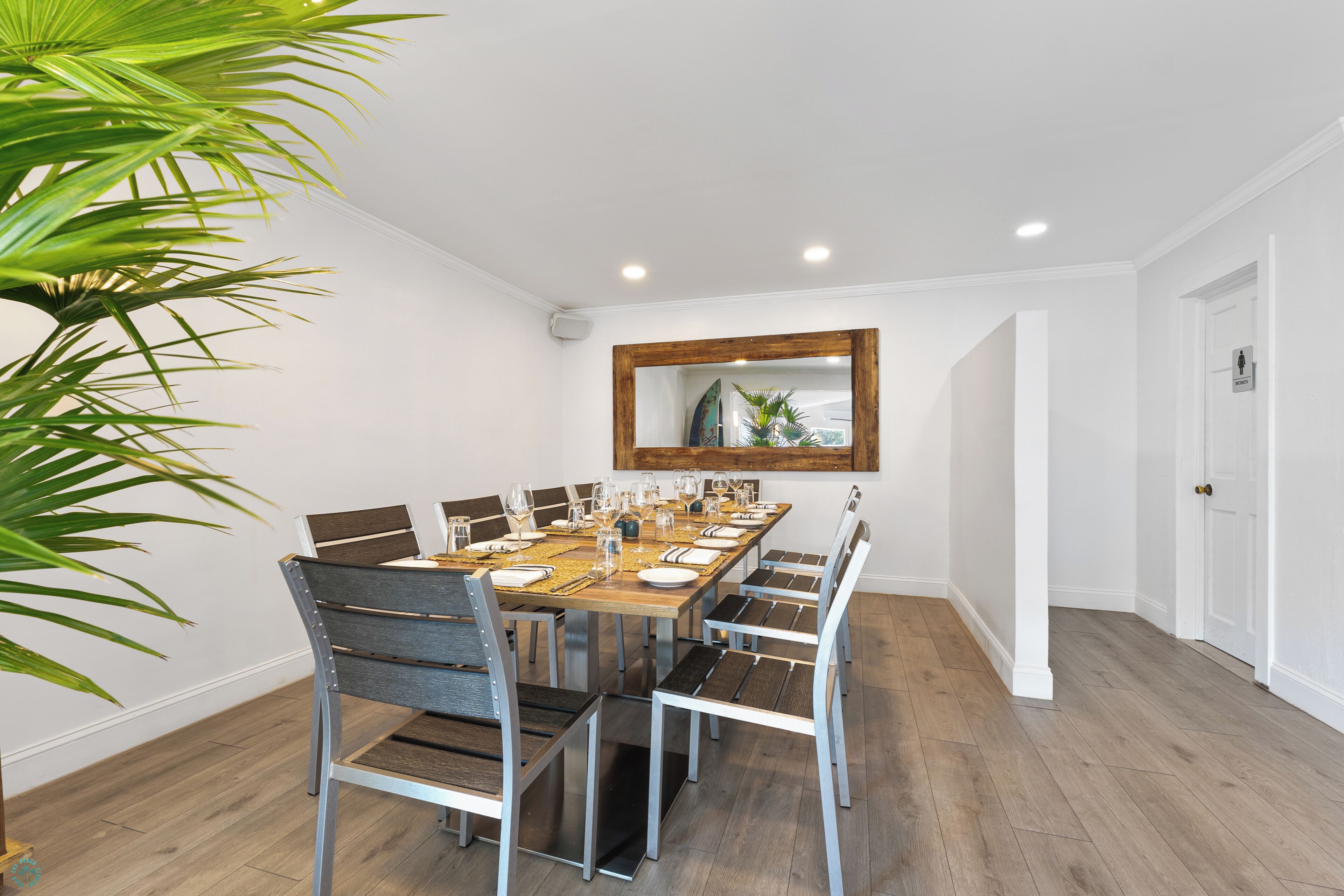 Une salle à manger avec une table en bois dressée pour six personnes, entourée de chaises en métal.