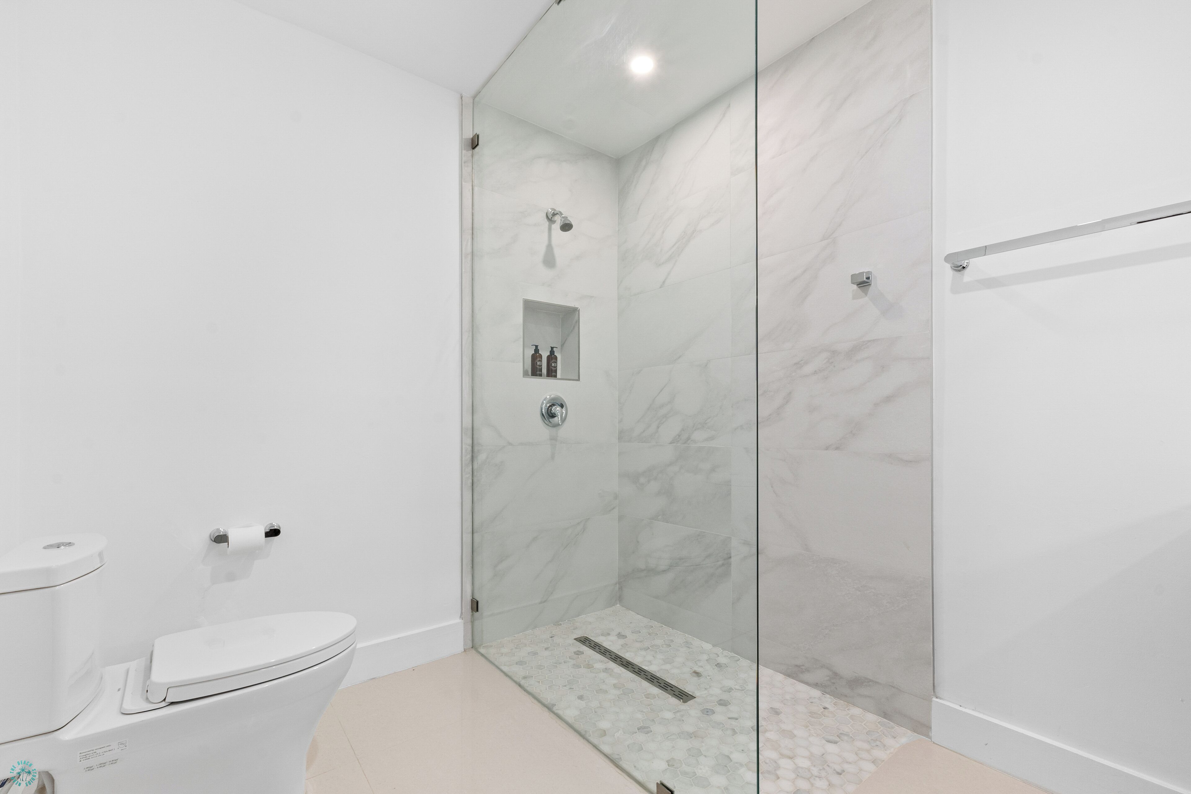A modern bathroom with a glass-enclosed shower, a toilet, and a sink.