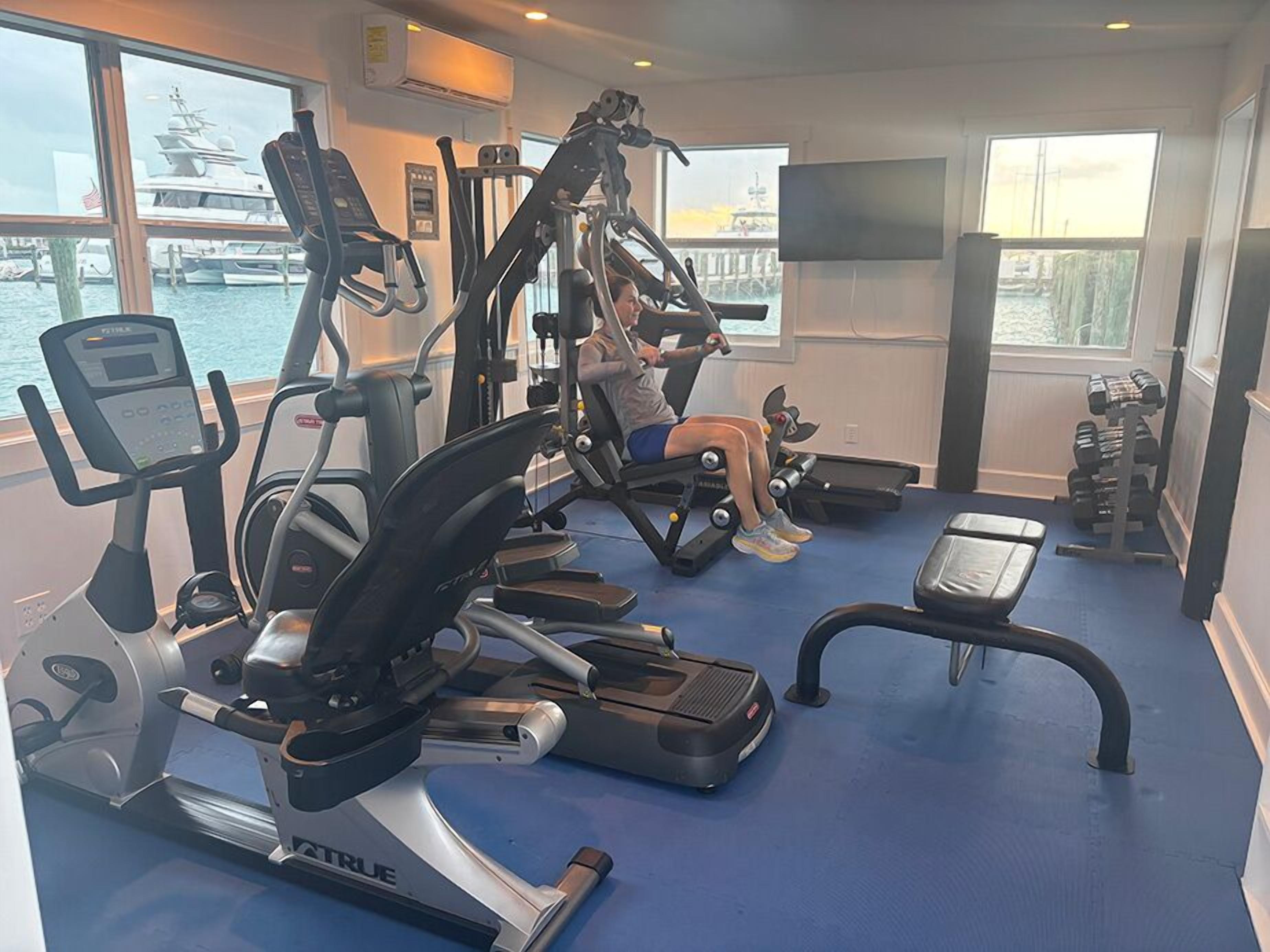 A gym with cardio machines, weight benches, and dumbbells.