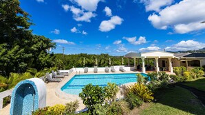 A swimming pool with lounge chairs and a covered patio area. - Siesta Hotel (St. George's)